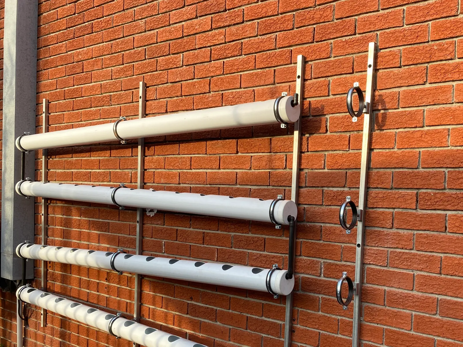 Uprights fixed to a brick wall with the first channels clamped in place and the remaining brackets empty